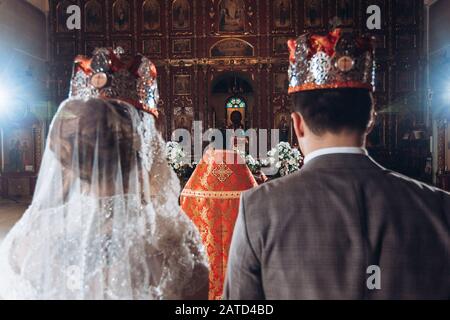 Coppia fiabesca, sposa e sposo in corone durante la cerimonia nuziale in chiesa Foto Stock