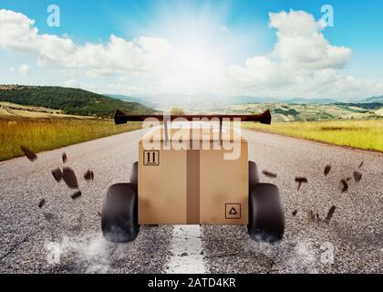 Priorità di scatola di cartone con ruote da corsa come un automobile. Spedizione veloce su strada. Foto Stock