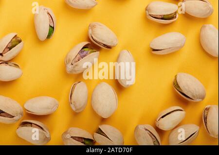 Pistacchi secchi in guscio su fondo giallo Foto Stock