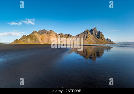 Panorama epico della spiaggia di sabbia nera a Stokksnes in una giornata di sole. Il monte Vestrahorn sullo sfondo. Natura ed ecologia di concetto di fondo. Foto Stock