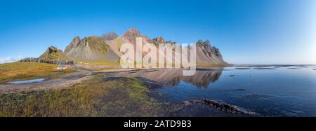 Panorama epico della spiaggia di sabbia nera a Stokksnes in una giornata di sole. Il monte Vestrahorn sullo sfondo. Natura ed ecologia di concetto di fondo. Foto Stock