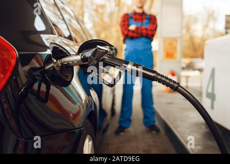 Lavoratore maschile in uniforme alimenta veicolo, stazione di benzina Foto Stock