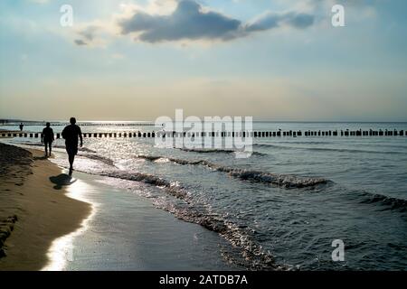 Vacanzieri sulla spiaggia del Mar Baltico vicino a Rewal in Polonia nella retroilluminazione Foto Stock