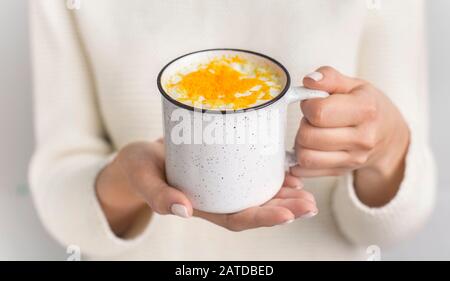 Donna irriconoscibile che tiene il latte dorato fatto con curcuma Foto Stock