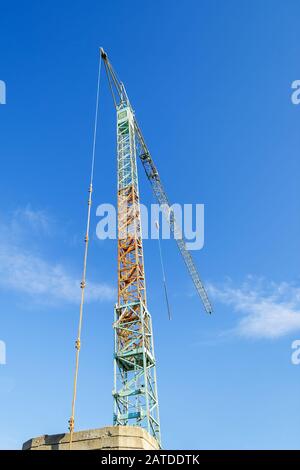 Gru a torre blu gialla contro il cielo azzurro in una giornata invernale soleggiata. Macchinari da costruzione moderni. Vista ad angolo basso. Foto Stock