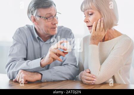 Uomo maturo che dà alla moglie alcune pillole Foto Stock