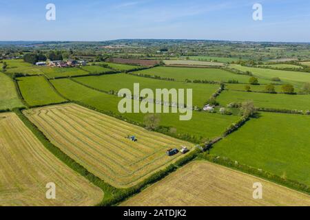 Una foto aerea scattata da un drone di agricoltori che raccolgono erba per la produzione di insilato nel Wiltshire. Foto Stock