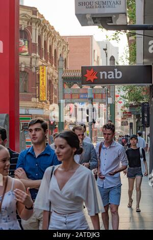 Le persone che camminano sotto un cartello con il logo della National Australia Bank (Nab Bank) fuori da una filiale della città in Melbourne Australia Foto Stock