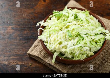 Tritate finemente la verza in una piastra su un sfondo di legno. spazio per il testo Foto Stock