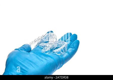 La mano contiene un set di vassoi dentari personalizzati per la sbianca dei denti. Isolato su sfondo bianco Foto Stock