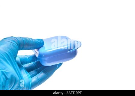 La mano dello stomatologo sta tenendo il contenitore blu per il vassoio dentale personalizzato Foto Stock