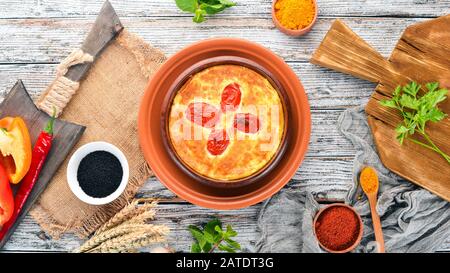 Formaggio cotto con pomodori in un piatto. Cucina georgiana. Sul vecchio sfondo di legno. Spazio libero per il testo. Vista dall'alto. Foto Stock