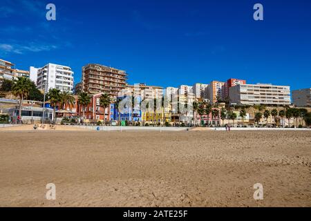 Spiaggia, blocchi colorati di appartamenti a torre e sole invernale a Villajoyosa, Costa Blanca, Alicante, Spagna Foto Stock