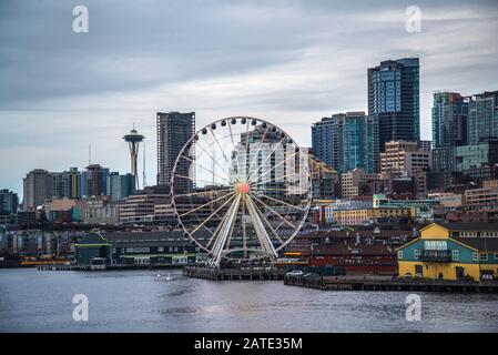 Lungomare e skyline di Seattle, con lo Space Needle che mostra attraverso i raggi della ruota della Grande ruota panoramica in primo piano. Immagine colorata Foto Stock