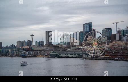 Lungomare e skyline di Seattle, con lo Space Needle che mostra attraverso i raggi della ruota della Grande ruota panoramica in primo piano. Immagine colorata Foto Stock