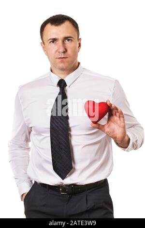 Un uomo tiene un giocattolo a forma di cuore nelle sue mani, isolato su uno sfondo bianco. Il concetto di diagnosi di malattie cardiovascolari in ufficio dipendente Foto Stock
