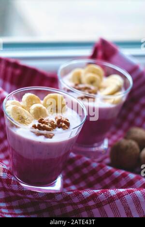 Un bicchiere di yogurt con mirtilli, cereali, banana e noci Foto Stock