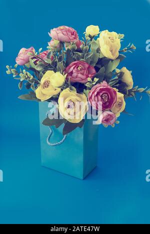 Bouquet di fiori in un sacchetto di carta su sfondo blu Foto Stock