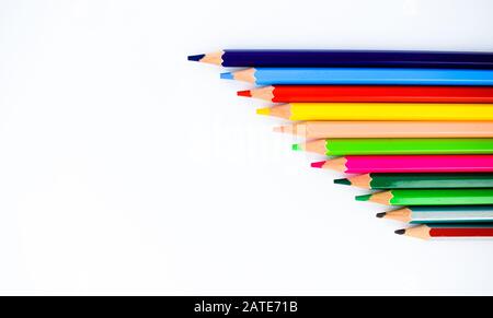 Mazzo di pastelli di matita colorati diversi disposti da piccolo a grande su uno sfondo bianco Foto Stock