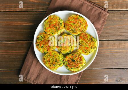 Cotolette vegetali di zucchine, carote, erbe in piatto bianco. Vista dall'alto, piatto Foto Stock