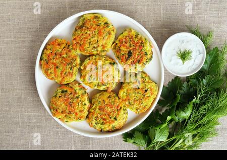 Gustosi cotolette di verdure da zucchine, carote, erbe in piatto bianco. Vista dall'alto, piatto Foto Stock