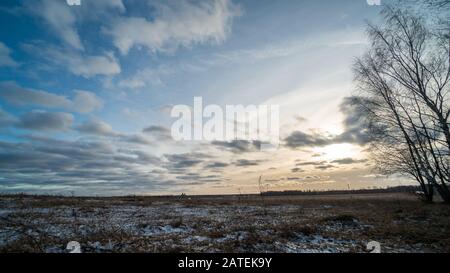 Bella impostazione del sole su campo ghiacciato Foto Stock