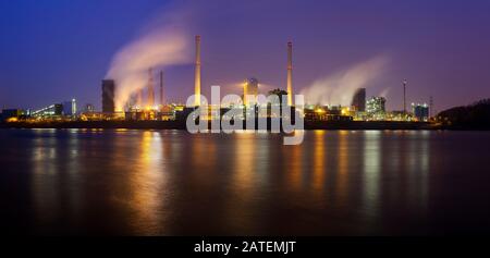 Panorama di una pianta di coking vista su un fiume con un sacco di vapore e cielo blu notte. Foto Stock