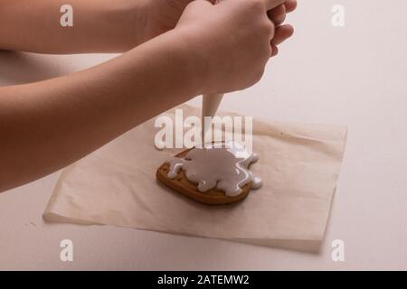 Un ragazzo di 10 anni smala i biscotti con una borsa culinaria. Fatto A Mano. Creatività dei bambini Foto Stock