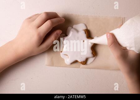 Un ragazzo di 10 anni smala i biscotti con una borsa culinaria. Fatto A Mano. Creatività dei bambini Foto Stock