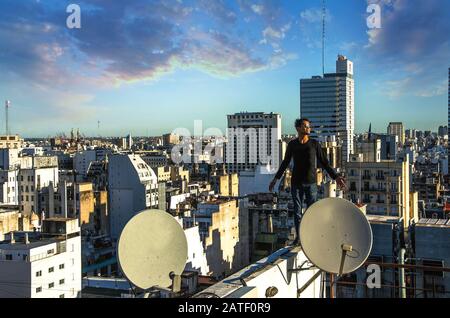 Buenos Aires, Argentina, - Febbraio. 20. 2016: Uomo che si erge sul tetto e guarda il panorama urbano della città al tramonto. Foto Stock