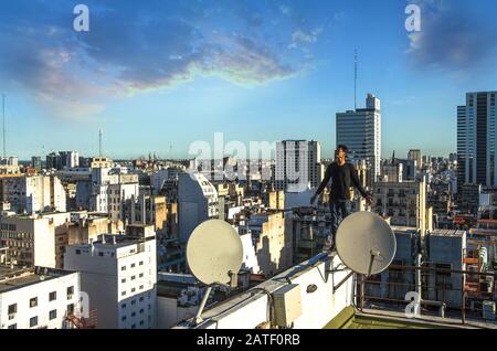 Buenos Aires, Argentina, - Febbraio. 20. 2016: Uomo che si erge sul tetto e guarda il panorama urbano della città al tramonto. Foto Stock