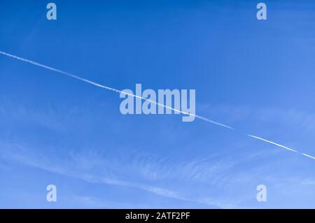 Chemtrail su cielo azzurro leggermente nuvoloso - texture sfondo Foto Stock