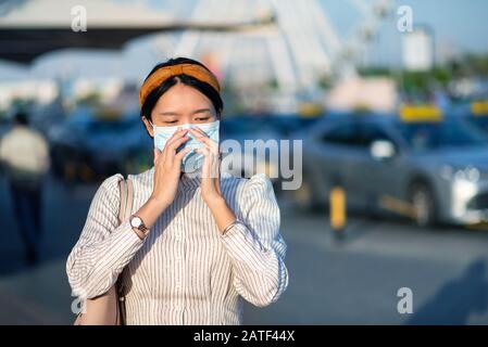 Ragazza asiatica che indossa maschera facciale in un parcheggio all'aperto Foto Stock