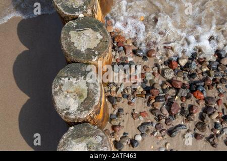 Groynes con pietre lavate sulla spiaggia del Mar Baltico nella località balneare di Zempin su Usedom Foto Stock