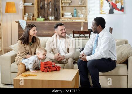 Allegro consigliere e famiglia che si riuniscono sul divano Foto Stock