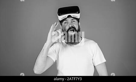 Uomo con barba lunga e viso divertente che mostra il gesto OK. Hippster con la barba alla moda che indossa occhiali VR, concetto di tecnologie digitali. Bearded man test 3D video plugin isolato su sfondo blu. Foto Stock