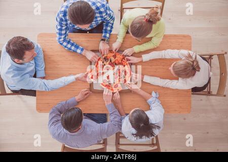 Le persone in fette di pizza da tavolo in legno, vista dall'alto Foto Stock