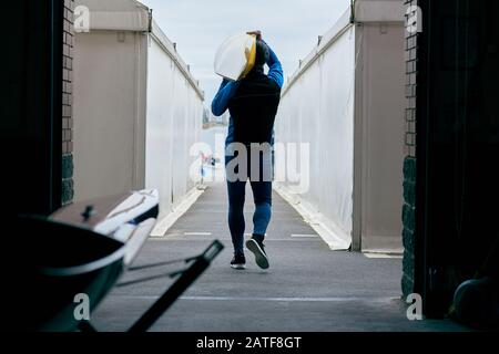 Vista posteriore dell'atleta maschile irriconoscibile che porta la barca sulla spalla Foto Stock