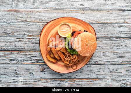 Hamburger con carne, cipolla, pomodori e patate al forno. Sul vecchio sfondo. Spazio libero di copia. Vista dall'alto. Foto Stock