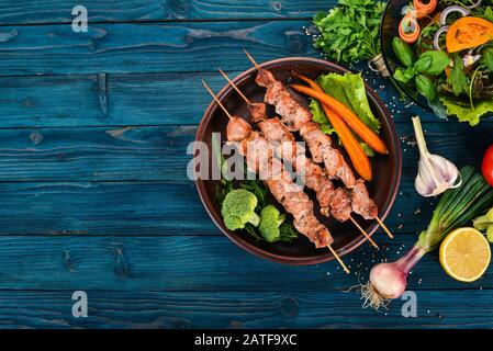 Spiedini di carne cotti su un piatto. Su uno sfondo di legno. Vista dall'alto. Spazio di copia. Foto Stock