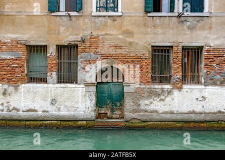 Una vecchia porta verde in un vecchio magazzino si affaccia sul rio de San Marcuola canale Cannaregio, Venezia, Italia Foto Stock