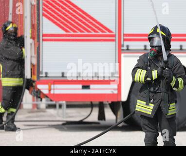 pompieri con idrante in azione e motore antincendio sullo sfondo Foto Stock