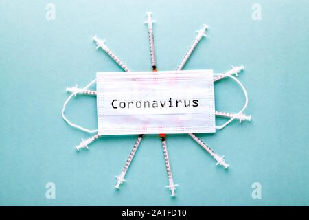 iscrizione coronavirus su maschera medica protettiva e siringhe per insulina, immagine su sfondo blu Foto Stock