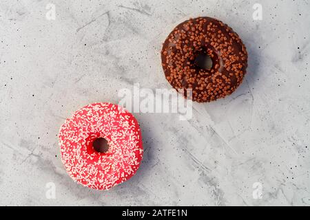 Deliziose ciambelle al cioccolato e alla crema su una superficie grigia in cemento. Foto Stock