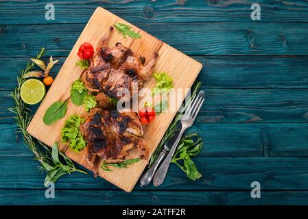 Quaglia cotta con verdure su tavola di legno. Su uno sfondo di legno. Vista dall'alto. Spazio di copia. Foto Stock