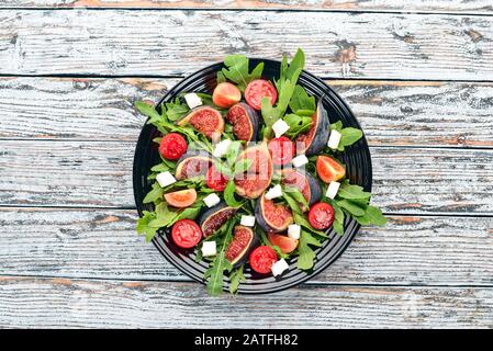 Insalata fresca con fichi, foglie di rucola, pomodori ciliegini e formaggio feta. Spazio libero per il testo. Vista dall'alto. Foto Stock