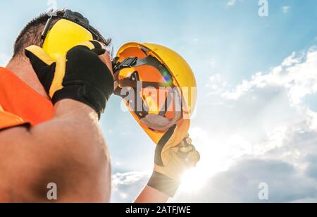 Protezione Per Le Teste Del Settore Edile. Lavoratore Caucasico Con Casco Giallo E Cuffie Antirumore. Foto Stock