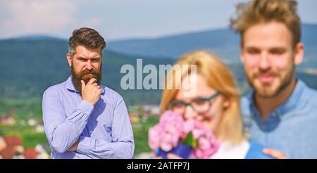 Gli amanti abbracci outdoor flirt romanticismo relazioni. Concetto di infedeltà. Coppia romantica data amanti fiori bouquet. Coppia nell'amore che datano mentre l'uomo geloso bearded che guarda la moglie che lo bardisce con l'amante. Foto Stock