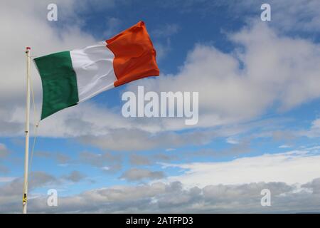 Bandiera irlandese isolata con cielo blu e sfondo nuvoloso Foto Stock
