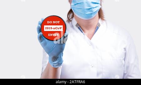 La mano del medico femminile che tiene il segno di arresto con il testo non entra nel coronavirus 2019-nCoV contro l'immagine concettuale di sfondo rosso. Foto Stock
